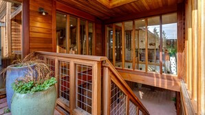 Un interior de madera con ventanas amplias, una escalera de madera y una planta en maceta.