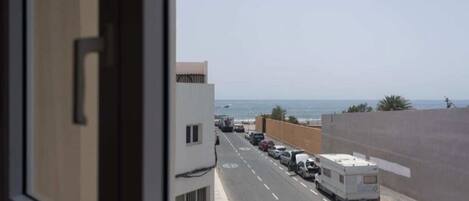 Vista de la calle con vehículos estacionados y un edificio al fondo.