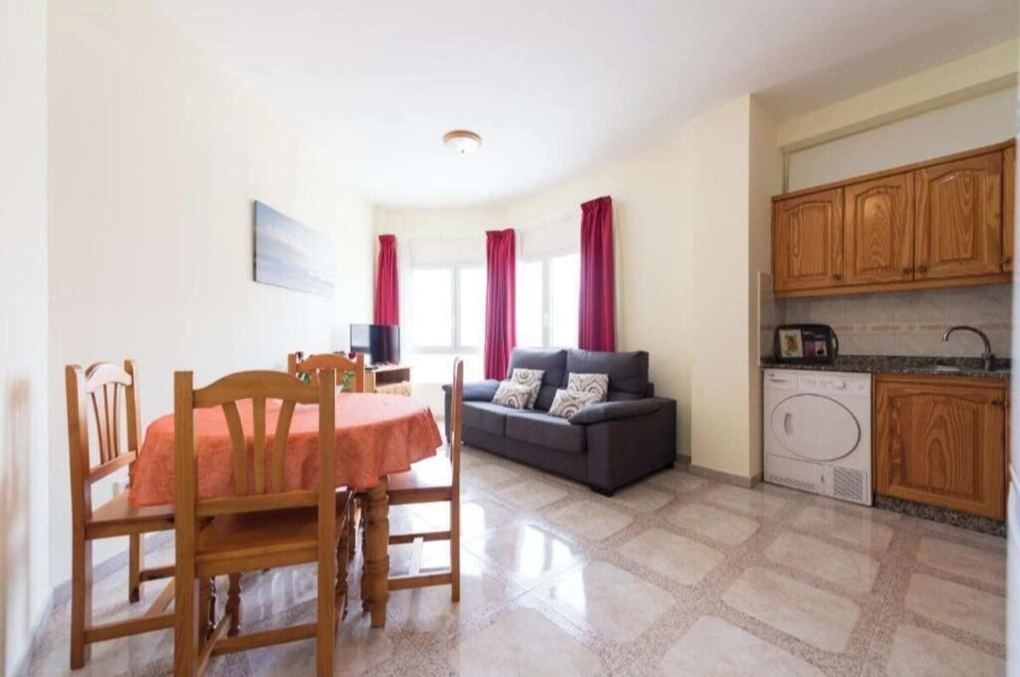 A compact living space with a dining area, a sofa, a washing machine, and wooden cabinets.