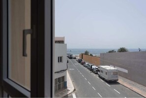 A street with parked vehicles and a view of the sea. - B - 2-bedroom apartment with sea view B (Castillo del Romeral)