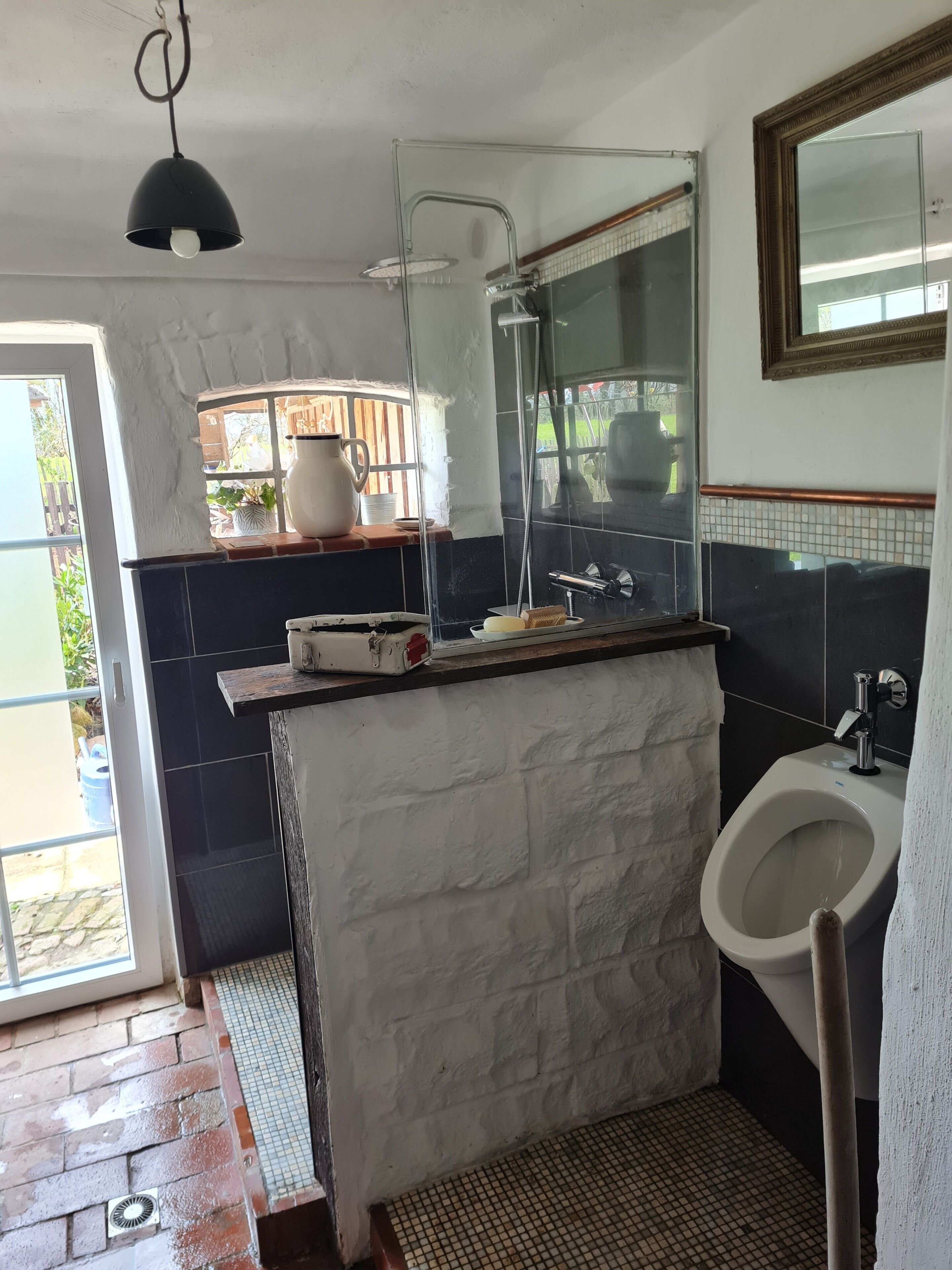 A bathroom with a shower, a sink, a mirror, and a window.