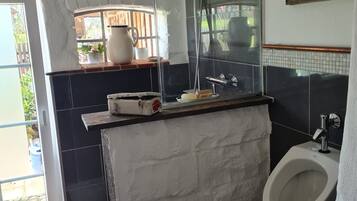 A bathroom with a shower, a sink, a mirror, and a window.
