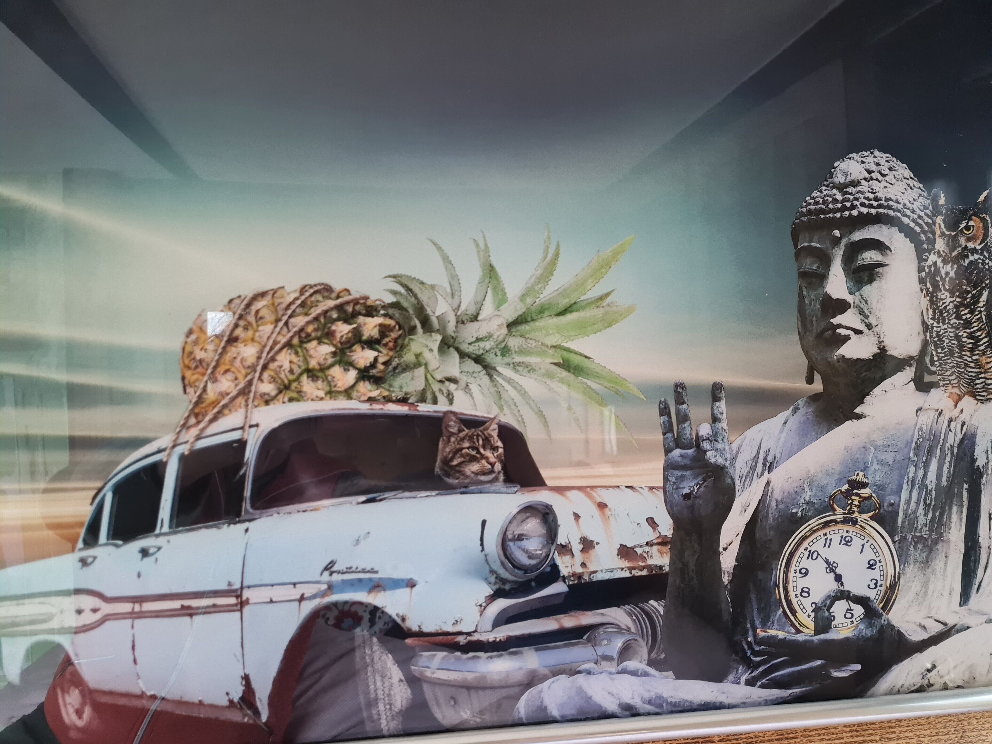 Eine Statue einer sitzenden Figur mit einer Uhr, ein Auto mit einer Ananas auf dem Dach und eine Pflanze.