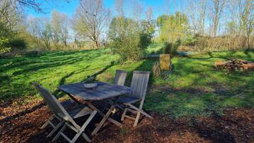 A wooden table and chairs in a garden with a clear sky.