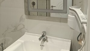 A bathroom with a white sink, a mirror, and a shower area. - Rezidenca Pahumi 2 (Durrës)