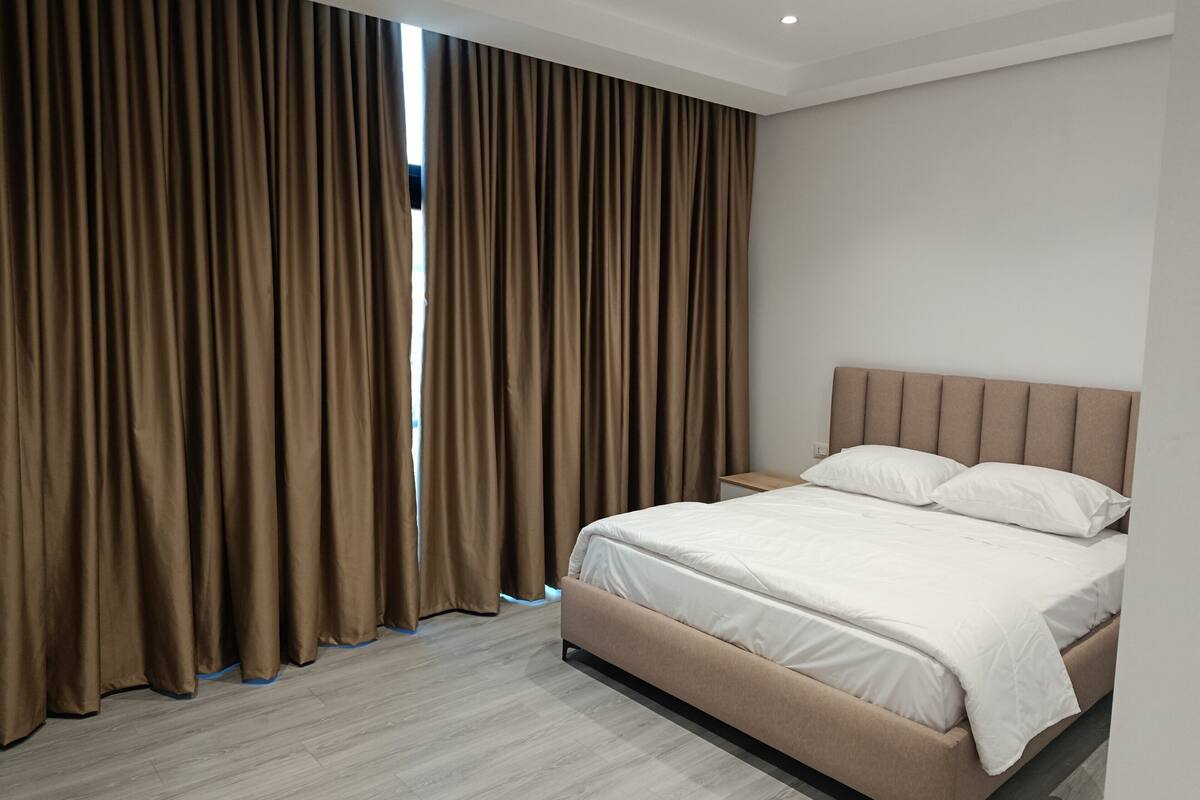 A bedroom with a bed, curtains, and a nightstand.