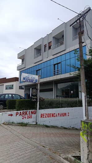 Un hôtel avec une enseigne indiquant la présence d’un bar et d’un café, un panneau de signalisation pour le stationnement et un bâtiment doté de grandes fenêtres.