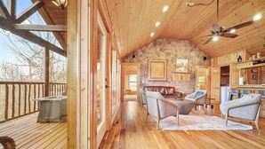 Un intérieur en bois avec une cheminée en pierre, un coin repas avec des chaises et un espace cuisine.