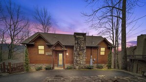 Une cabane en rondins avec une cheminée en pierre, une porte d’entrée et une enseigne indiquant qu’il s’agit d’un établissement proposant l’hébergement et le petit-déjeuner.