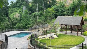 Une piscine, un kiosque en bois et un jardin clos.