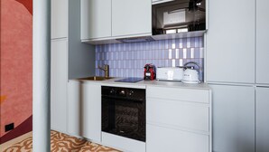 A modern kitchen with white cabinetry, a built-in oven, a microwave, and a kettle. - Stunning Flat 2 Bedrooms Sleeps 6 Canal Saint-martin (Paris)