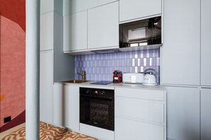 Eine moderne Küche mit weißen Schränken, einem Backofen, einer Mikrowelle und einem Wasserkocher.