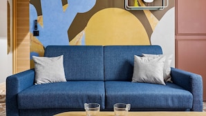 A blue sofa with two pillows, a wooden coffee table, and a wall with abstract art. - Stunning Flat 2 Bedrooms Sleeps 6 Canal Saint-martin (Paris)