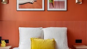 A bedroom with a bed, pillows, a nightstand, a wall-mounted light, and two framed pictures. - Stunning Flat 2 Bedrooms Sleeps 6 Canal Saint-martin (Paris)
