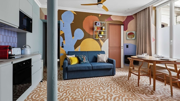 A modern living room with a sofa, a dining table, and a kitchen area. - Stunning Flat 2 Bedrooms Sleeps 6 Canal Saint-martin (Paris)