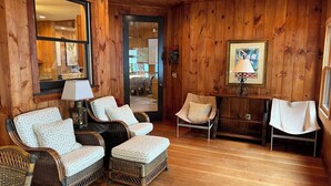 Una habitación con paneles de madera, muebles de mimbre, un espejo y un cuadro enmarcado.