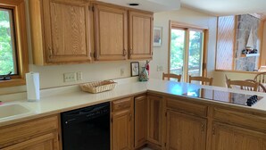 Una cocina con armarios de madera, lavavajillas, una isla grande y una zona de comedor con sillas.