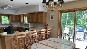Una cocina con armarios de madera, una isla central, una mesa de comedor con sillas y una araña.