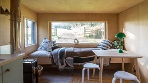 Una habitación acogedora con cama, mesa, silla, ventana con vistas al exterior y una lámpara en el techo.