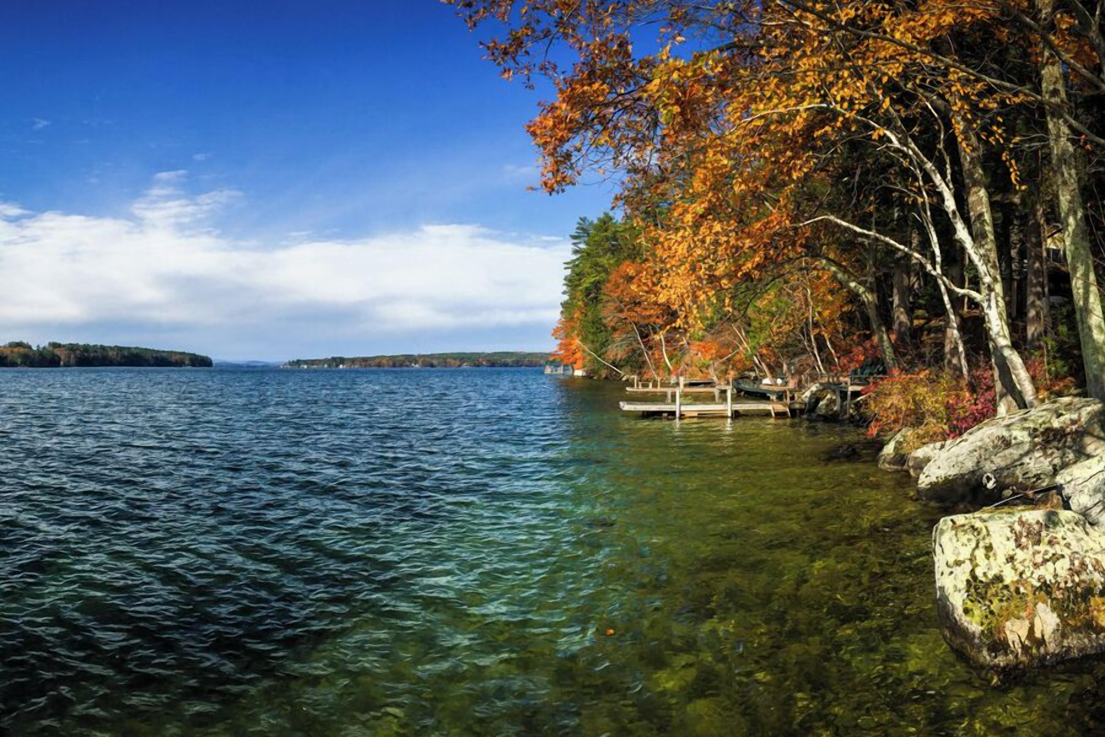 A clear lake with rocky shores and autumn foliage.