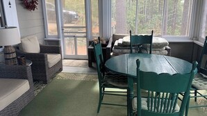 Una habitación con una mesa de comedor y sillas, un sofá, una lámpara y una guirnalda en la pared.