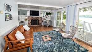 Un salon avec une cheminée, un canapé, un téléviseur et une vue sur l’extérieur.