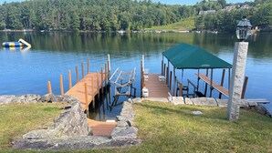 Una banchina di legno che si protende su un lago, con una zona coperta per sedersi e un lampione.