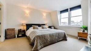 Une chambre à coucher avec un grand lit, des tables de chevet, une fenêtre donnant sur un beau paysage et un radiateur.