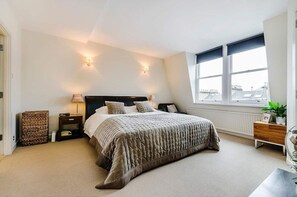 Ein Schlafzimmer mit einem großen Bett, Nachttischen, einem Fenster mit Ausblick und einer Heizung.
