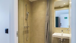 A bathroom with a shower, toilet, sink, and a mirror. - Easy Stay Næstved (Næstved)
