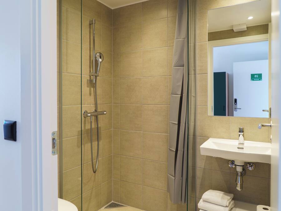 Un baño con ducha, inodoro, lavabo y espejo.