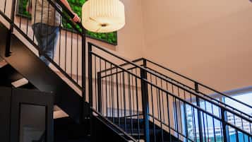 Un interior moderno con una escalera, una pared verde y una lámpara colgante.