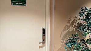 A hotel room door with a number sign indicating room 2, a keyhole, and a potted plant casting a shadow on the wall. - Easy Stay Næstved (Næstved)