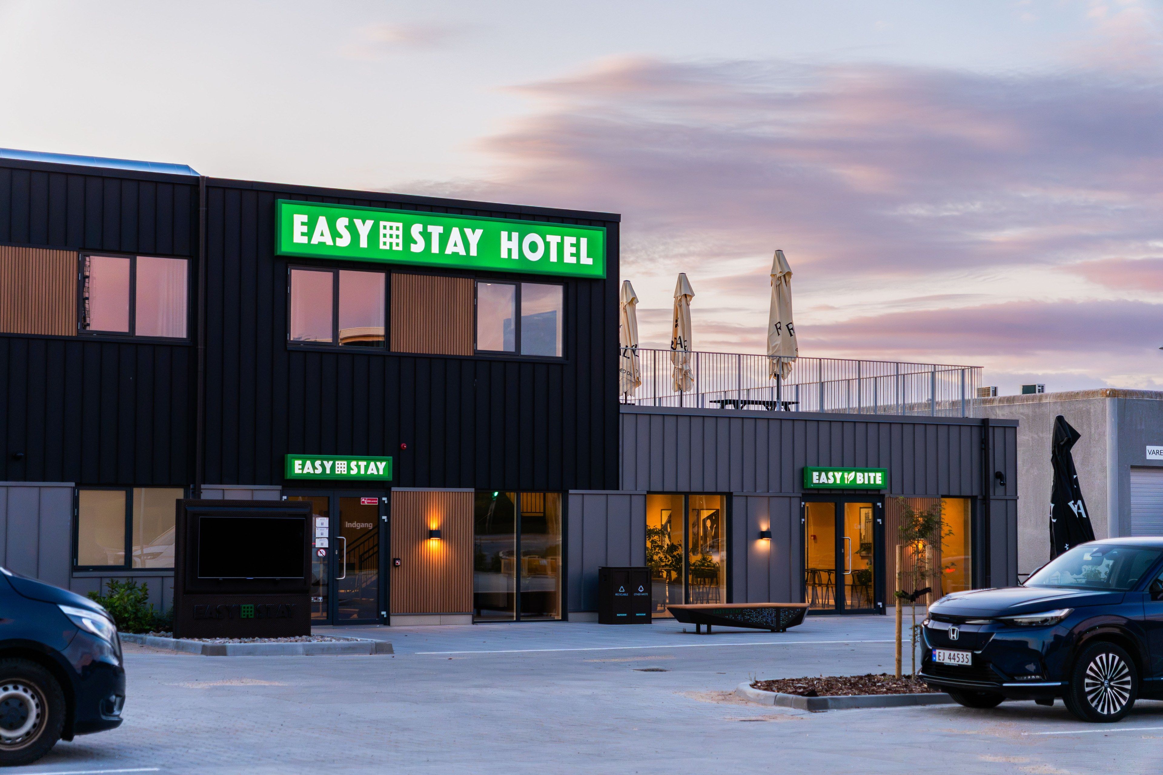 A modern building with a sign reading 'EASY STAY HOTEL' and another sign for 'EASY BITE'.