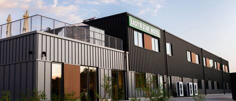 A modern hotel with a flat roof, large windows, and a sign that reads 'EASY STAY HOTEL'.