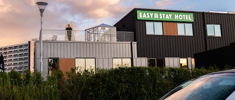 A modern hotel building with a sign reading 'EASY STAY HOTEL.'