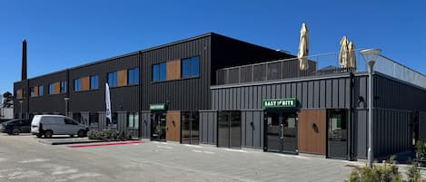 A modern building with a flat roof, large windows, and a red carpet leading to the entrance.