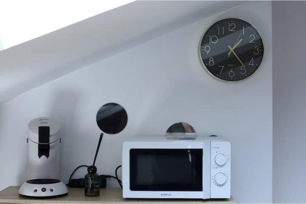A kitchen with a coffee maker, a microwave, and a wall clock.