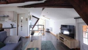 A modern living room with a sofa, TV, wooden cabinet, and a staircase leading to another room. - Charming rooftop cocoon in Vizille (Vizille)