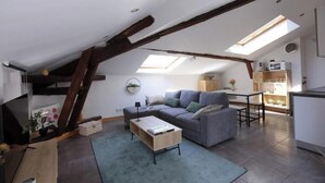 A loft-style living space with a sloped ceiling, a sofa, a coffee table, and a dining area. - Charming rooftop cocoon in Vizille (Vizille)