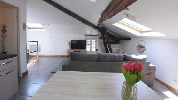 A modern interior with a dining area, a sofa, and a TV in the background. - Charming rooftop cocoon in Vizille (Vizille)