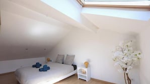 A bedroom with a skylight, a bed, a nightstand, and a potted plant. - Charming rooftop cocoon in Vizille (Vizille)