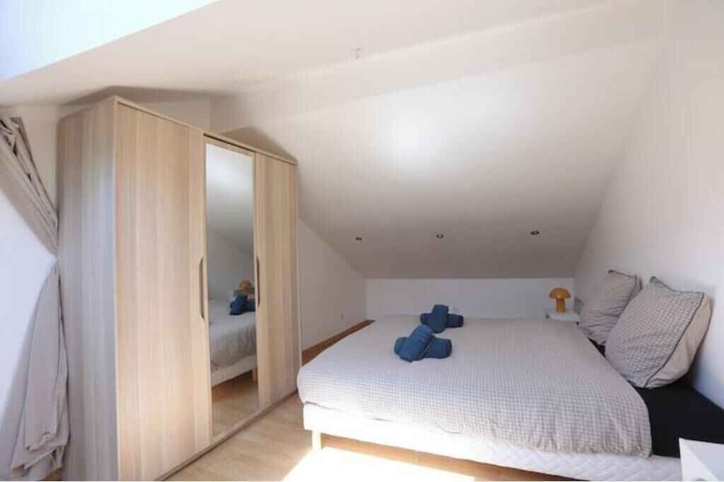 Um quarto com cama, guarda-roupa e mesa de cabeceira.