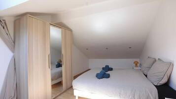 Um quarto com cama, guarda-roupa e mesa de cabeceira.