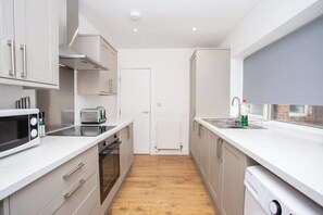 A modern kitchen with white cabinets, a microwave, a toaster, and a dishwasher.