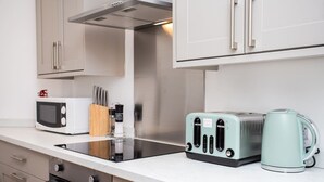 Eine Küche mit Mikrowelle, Toaster, Wasserkocher und einem Messerblock auf der Arbeitsfläche.