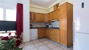 Eine kleine Küche mit Holzausstattung, einer Waschmaschine, einer Mikrowelle und einem Kühlschrank.
