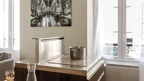 A modern kitchen with a stainless steel range hood, a pot on the countertop, and a large black and white artwork above the range hood. - Cocon du Château - Elegant T3 in the historic heart of Vizille (Vizille)