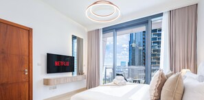 Een moderne hotelkamer met een groot bed, een flatscreen televisie, uitzicht over de stad en een houten kledingkast.
