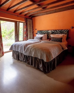 Une chambre à coucher avec un lit, des rideaux et une vue sur la verdure.